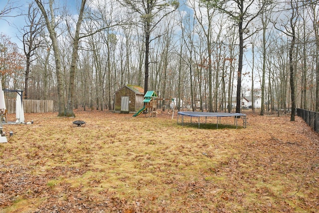 view of yard with a fenced backyard, an outbuilding, a playground, and a trampoline