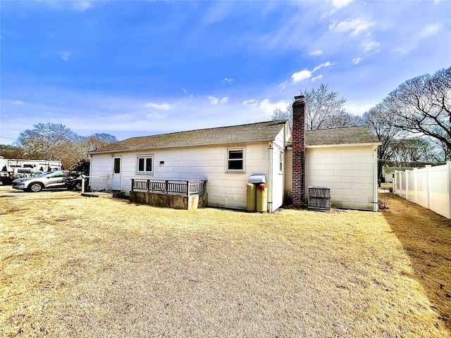 back of property with cooling unit, a chimney, and fence