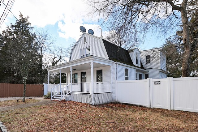 exterior space featuring a porch, fence, a gambrel roof, and a shingled roof