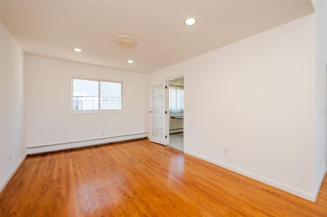 spare room featuring light wood finished floors, baseboards, and a baseboard radiator