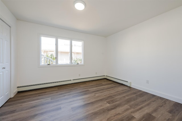 empty room with a baseboard heating unit, wood finished floors, and baseboards