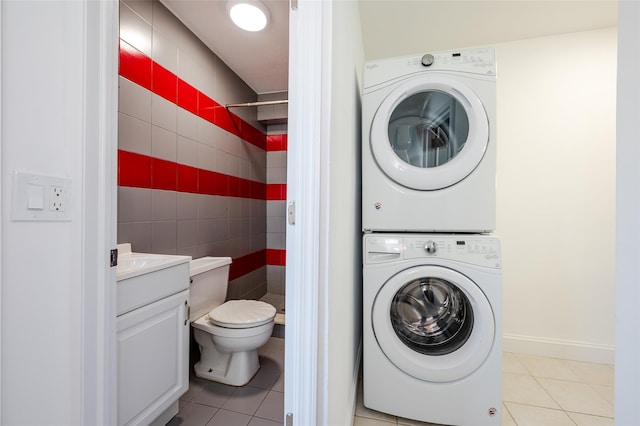 washroom with laundry area, light tile patterned flooring, tile walls, and stacked washer and clothes dryer