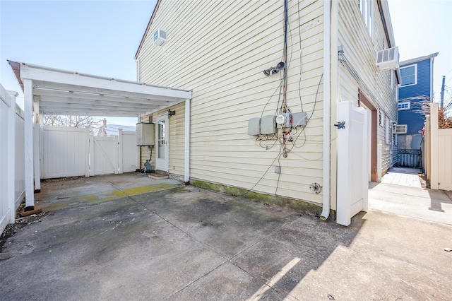 view of side of property featuring a gate, fence, driveway, a carport, and a patio area