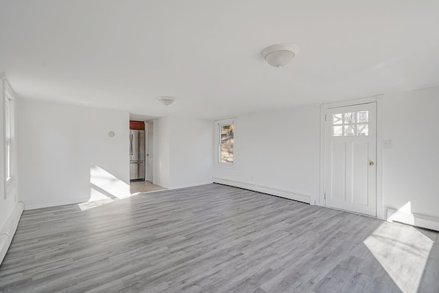 unfurnished living room featuring light wood-style floors and baseboard heating