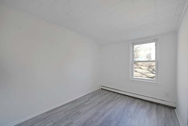 empty room featuring a baseboard radiator, baseboards, lofted ceiling, and wood finished floors