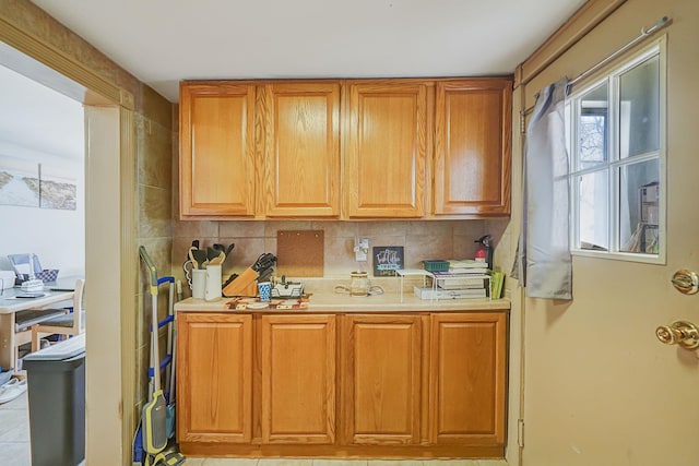 kitchen featuring decorative backsplash, light countertops, and brown cabinets