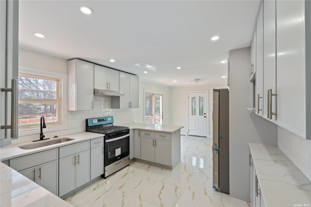 kitchen featuring under cabinet range hood, a peninsula, marble finish floor, stainless steel appliances, and a sink