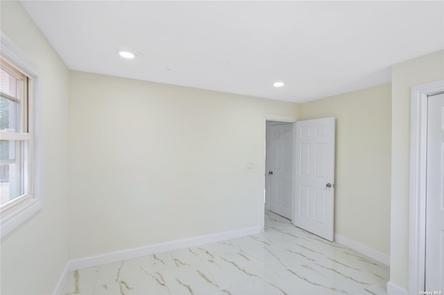 spare room featuring recessed lighting, baseboards, and marble finish floor