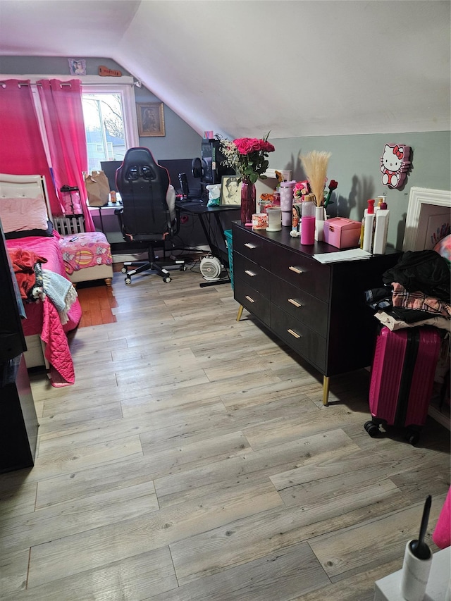 bedroom with lofted ceiling and light wood finished floors