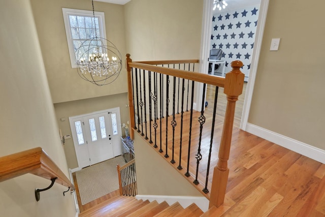 stairway featuring wood finished floors, baseboards, and a chandelier