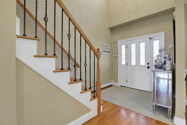 entryway featuring baseboards, stairs, a high ceiling, and wood finished floors