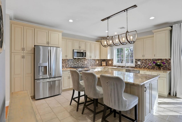 kitchen featuring crown molding, cream cabinets, appliances with stainless steel finishes, and a kitchen island