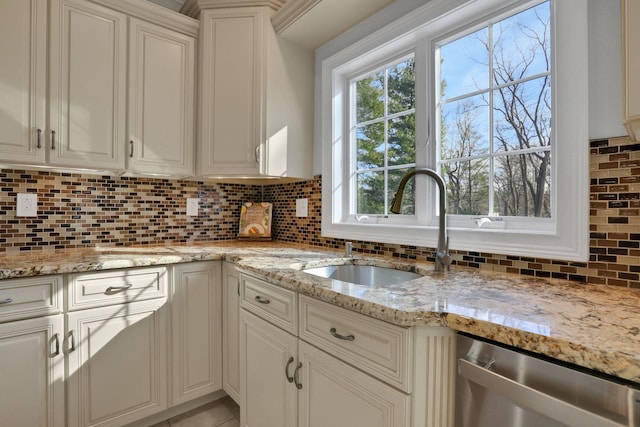 kitchen with dishwasher, light stone countertops, backsplash, and a sink