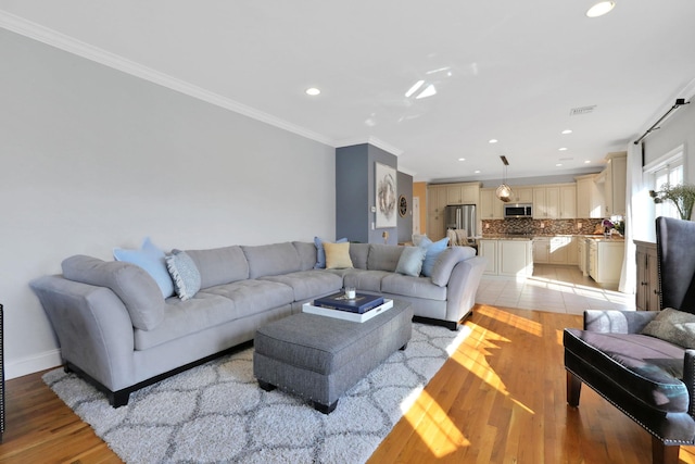 living area featuring light wood finished floors, recessed lighting, baseboards, and ornamental molding