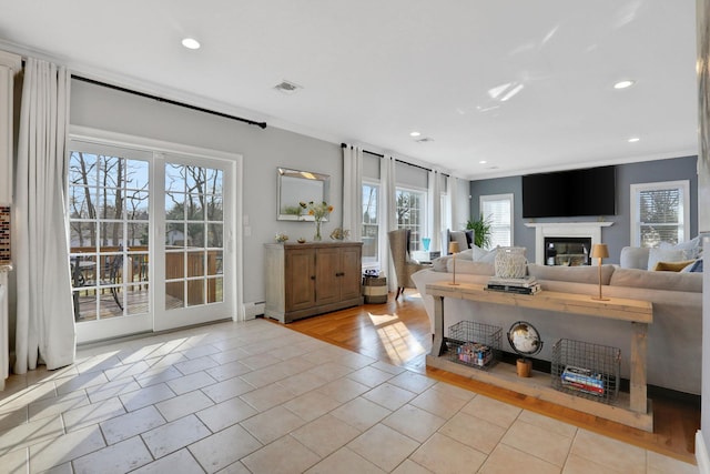 tiled living area featuring a glass covered fireplace, recessed lighting, a baseboard heating unit, and ornamental molding