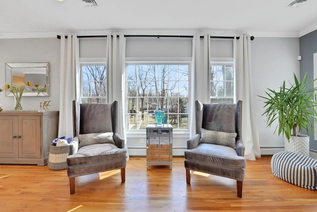 living area featuring a baseboard radiator, light wood-type flooring, and ornamental molding