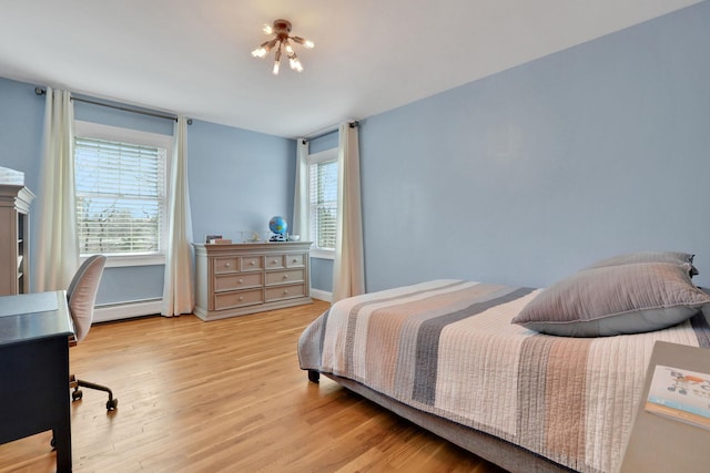 bedroom with a baseboard heating unit, an inviting chandelier, multiple windows, and wood finished floors