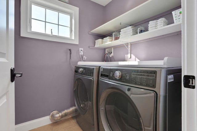 clothes washing area with tile patterned flooring, laundry area, baseboards, and washing machine and clothes dryer