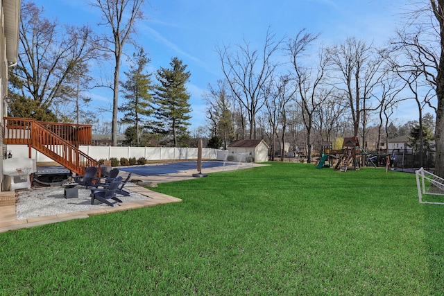 view of yard featuring an outbuilding, a fenced backyard, playground community, a storage shed, and a patio area