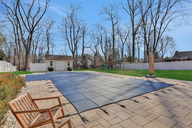 view of pool with an outdoor structure, a playground, a fenced backyard, and a patio