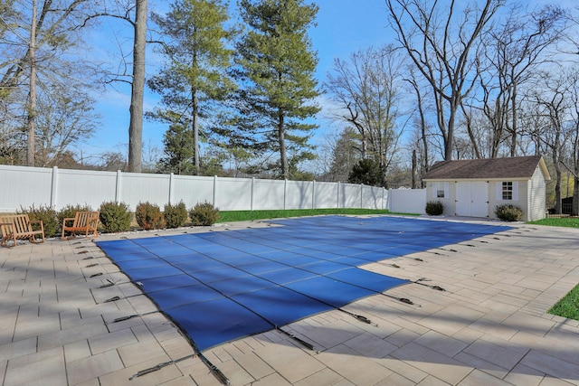 view of pool with a fenced backyard, a fenced in pool, an outdoor structure, and a patio area