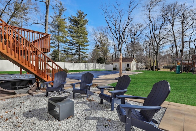 view of patio / terrace with a fire pit, an outbuilding, stairs, and fence