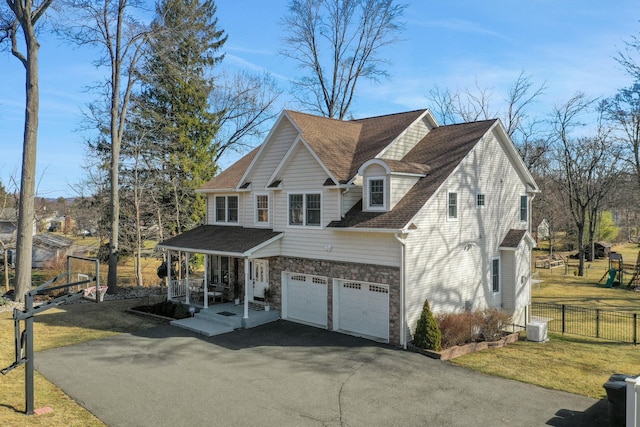 view of property exterior with aphalt driveway, stone siding, a garage, and covered porch