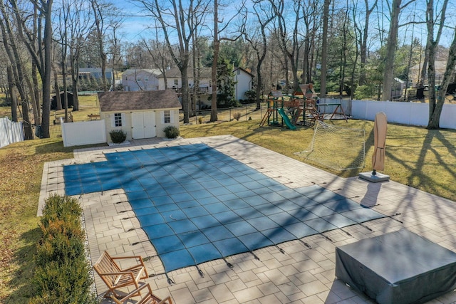 view of swimming pool featuring an outdoor structure, a playground, a yard, and a fenced backyard