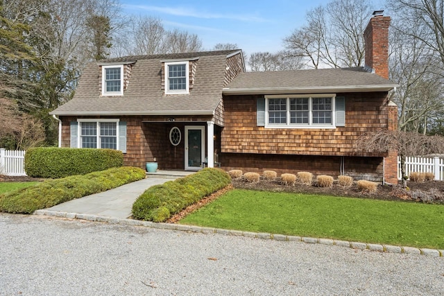 tri-level home featuring a front lawn, a chimney, roof with shingles, and fence