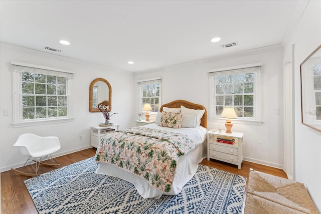 bedroom featuring crown molding, wood finished floors, visible vents, and baseboards