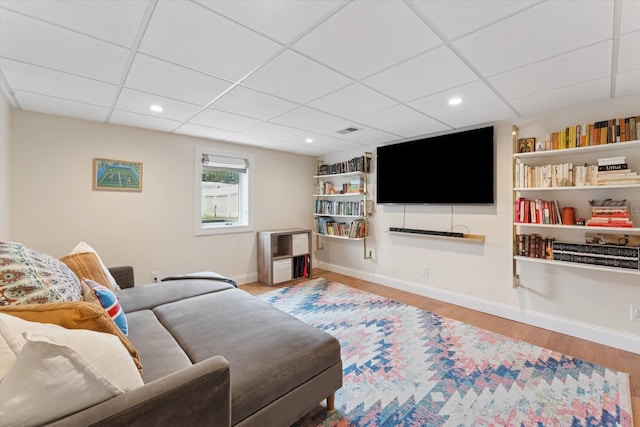 living area with visible vents, wood finished floors, recessed lighting, a paneled ceiling, and baseboards