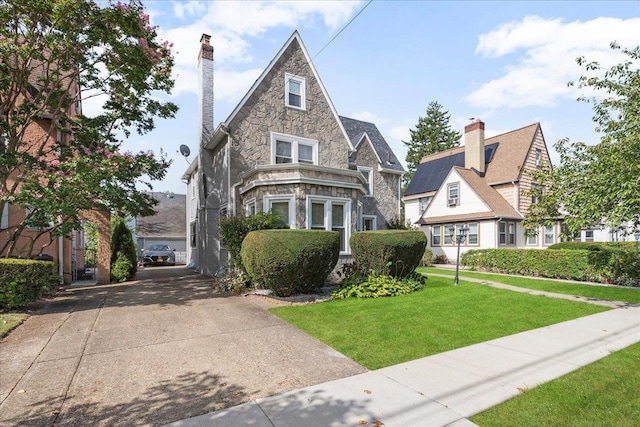 view of front facade with stone siding, a chimney, and a front lawn