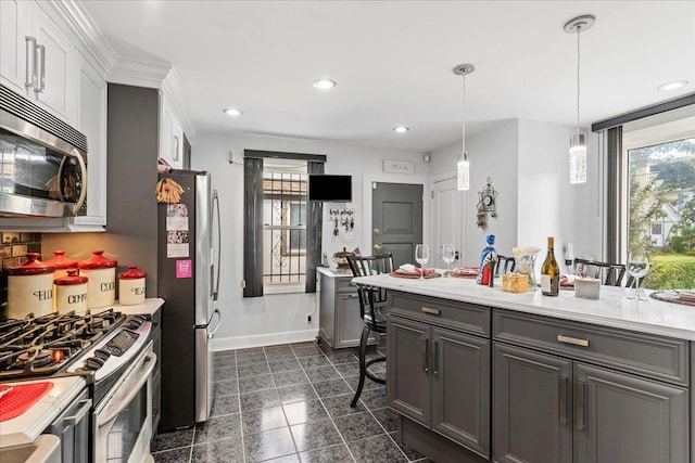 kitchen featuring a healthy amount of sunlight, appliances with stainless steel finishes, a breakfast bar, and gray cabinets