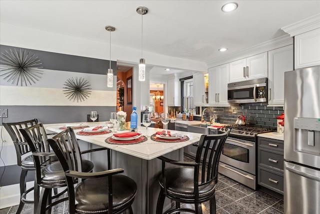 kitchen with a kitchen bar, light countertops, backsplash, and stainless steel appliances