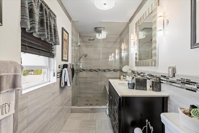 bathroom with vanity, tile walls, wainscoting, and a shower stall