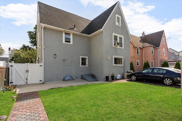 rear view of house featuring a gate, fence, a yard, cooling unit, and a shingled roof