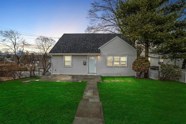 bungalow featuring roof with shingles, a fenced backyard, a front yard, and a patio area