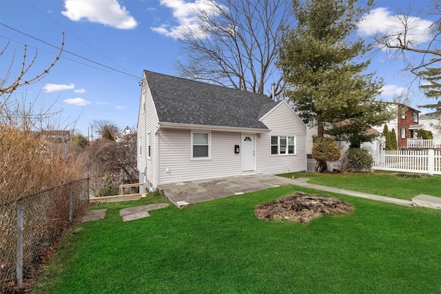 view of front of house with a front yard, a patio area, a fenced backyard, and roof with shingles