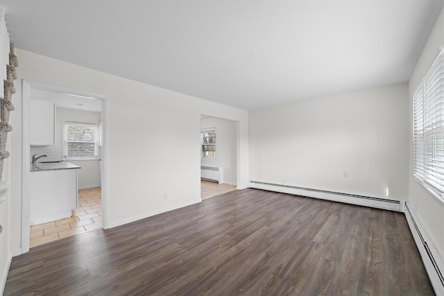 spare room featuring a baseboard heating unit, radiator, wood finished floors, and baseboards