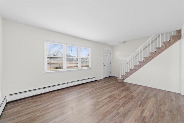 interior space featuring a baseboard radiator, baseboards, wood finished floors, and stairs