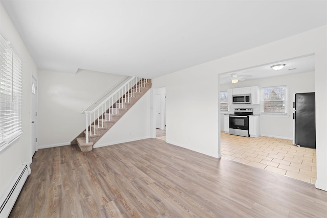 unfurnished living room featuring light wood-type flooring, stairs, a baseboard heating unit, and baseboards