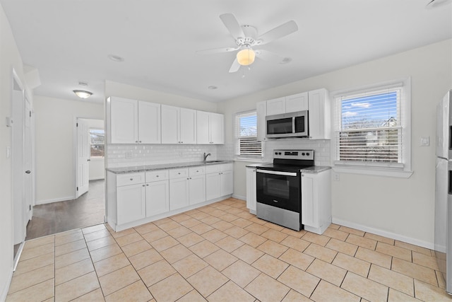 kitchen featuring a sink, tasteful backsplash, appliances with stainless steel finishes, white cabinets, and ceiling fan