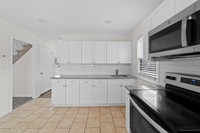 kitchen with white cabinets, backsplash, appliances with stainless steel finishes, and a sink