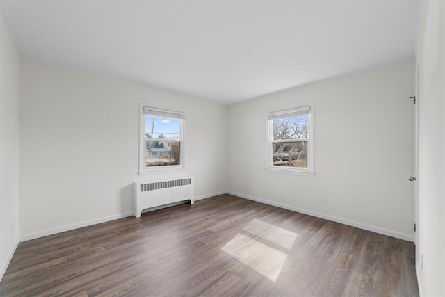 unfurnished room with plenty of natural light, radiator, and wood finished floors