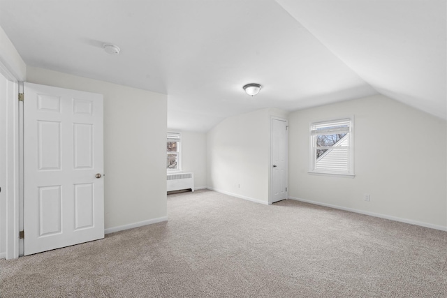 additional living space with baseboards, lofted ceiling, radiator, and carpet flooring