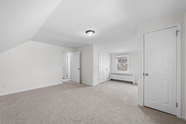 unfurnished bedroom with carpet flooring, vaulted ceiling, radiator heating unit, and baseboards