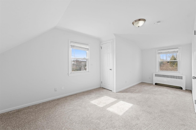 bonus room featuring vaulted ceiling, radiator heating unit, and a wealth of natural light