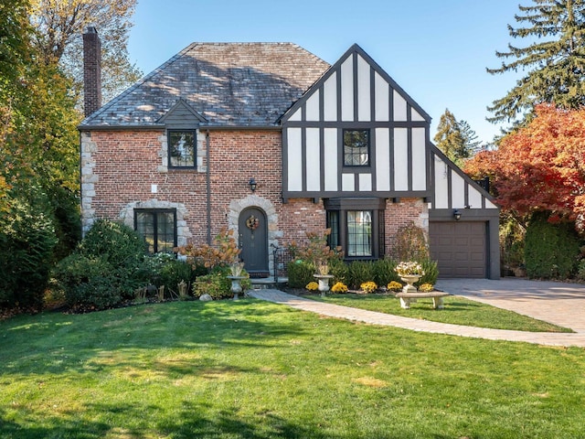 tudor home with brick siding, a high end roof, a front yard, a chimney, and driveway