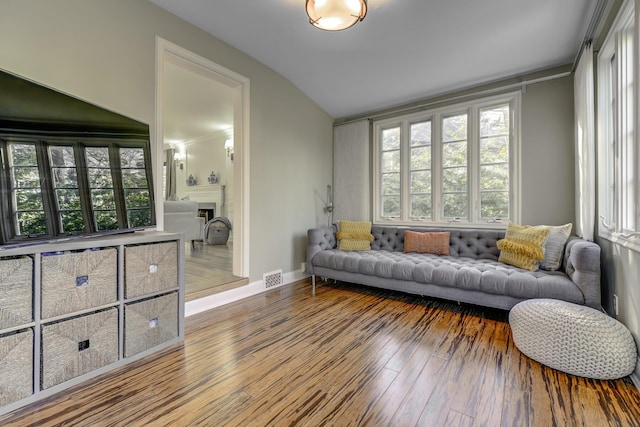 living area featuring lofted ceiling, baseboards, visible vents, and wood-type flooring