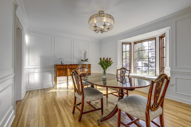 dining room featuring a decorative wall, light wood-style floors, and ornamental molding